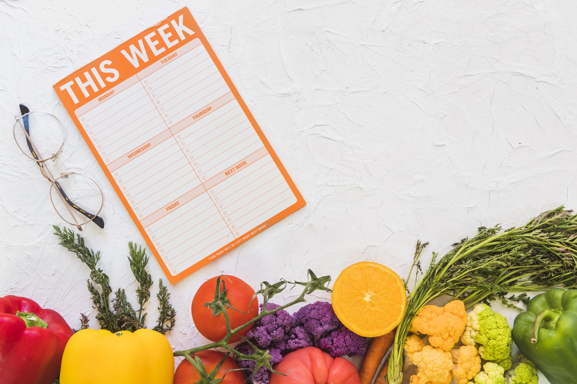 Weekly menu highlighting a variety of fresh vegetables and fruits, presented on a rustic wooden surface.