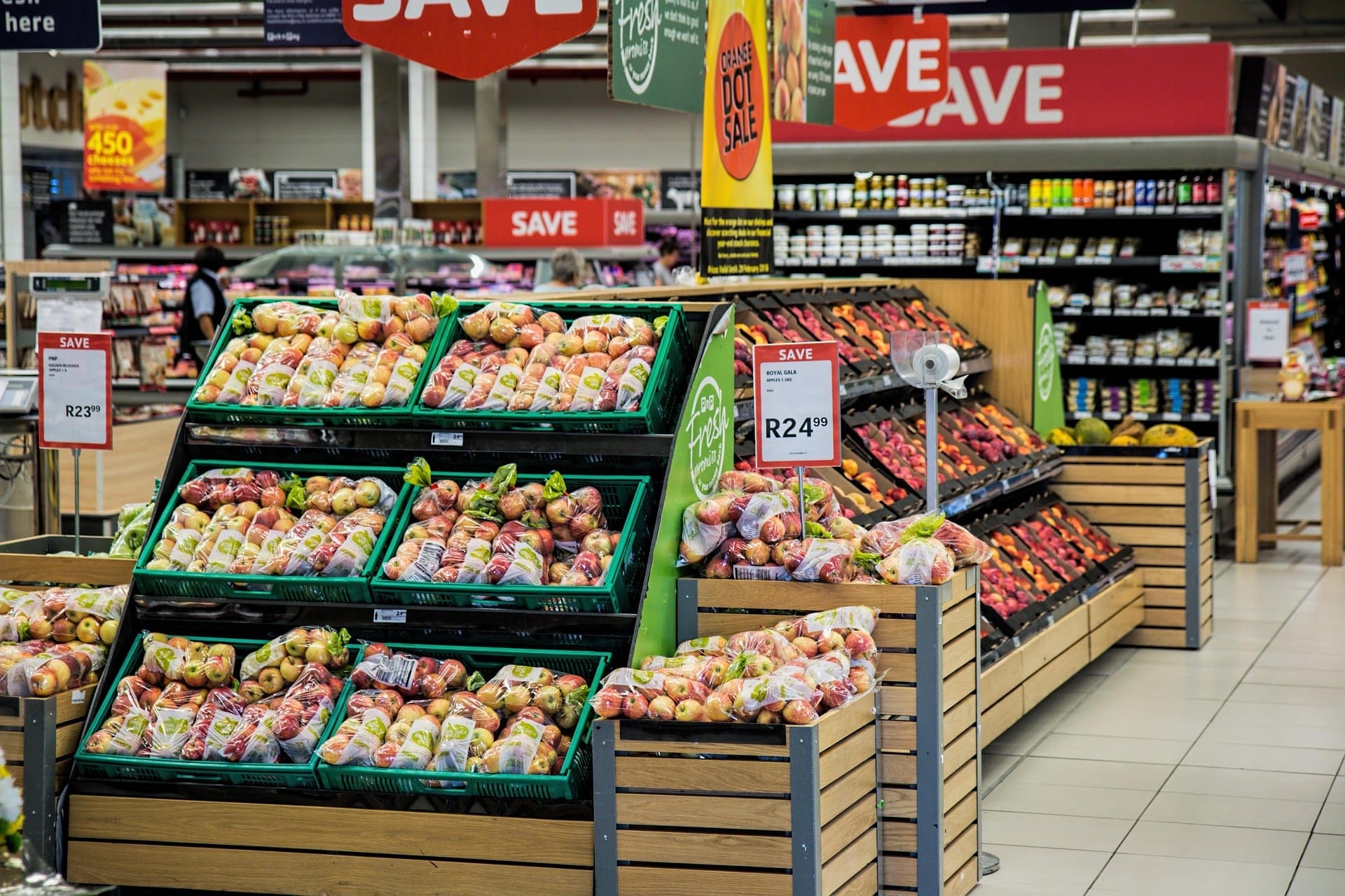A store aisle displaying fresh fruits and various grocery items on shelves.