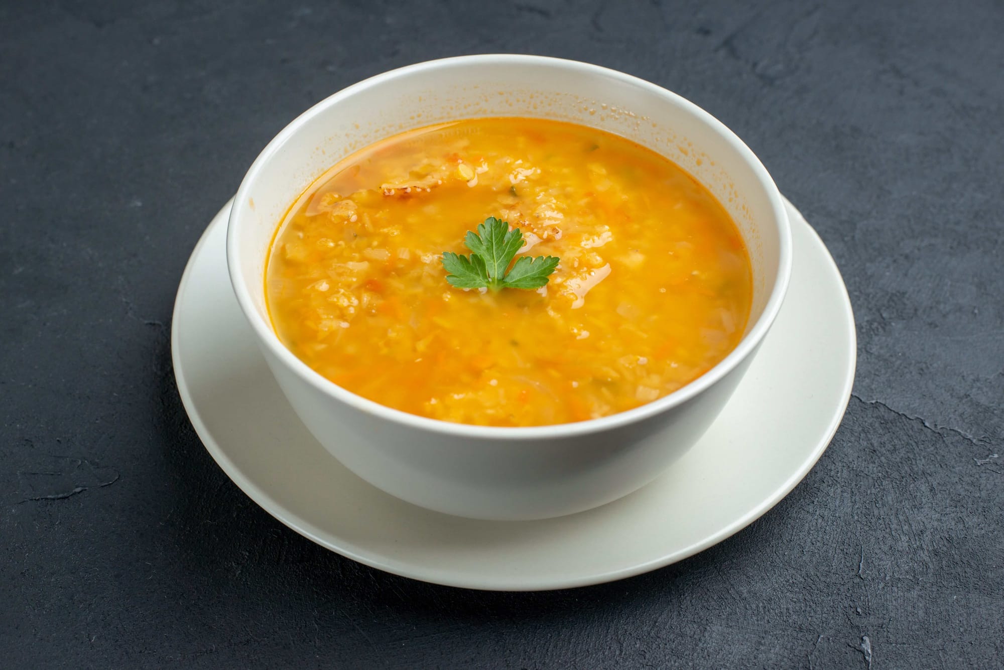 A white bowl with red lentil soup.